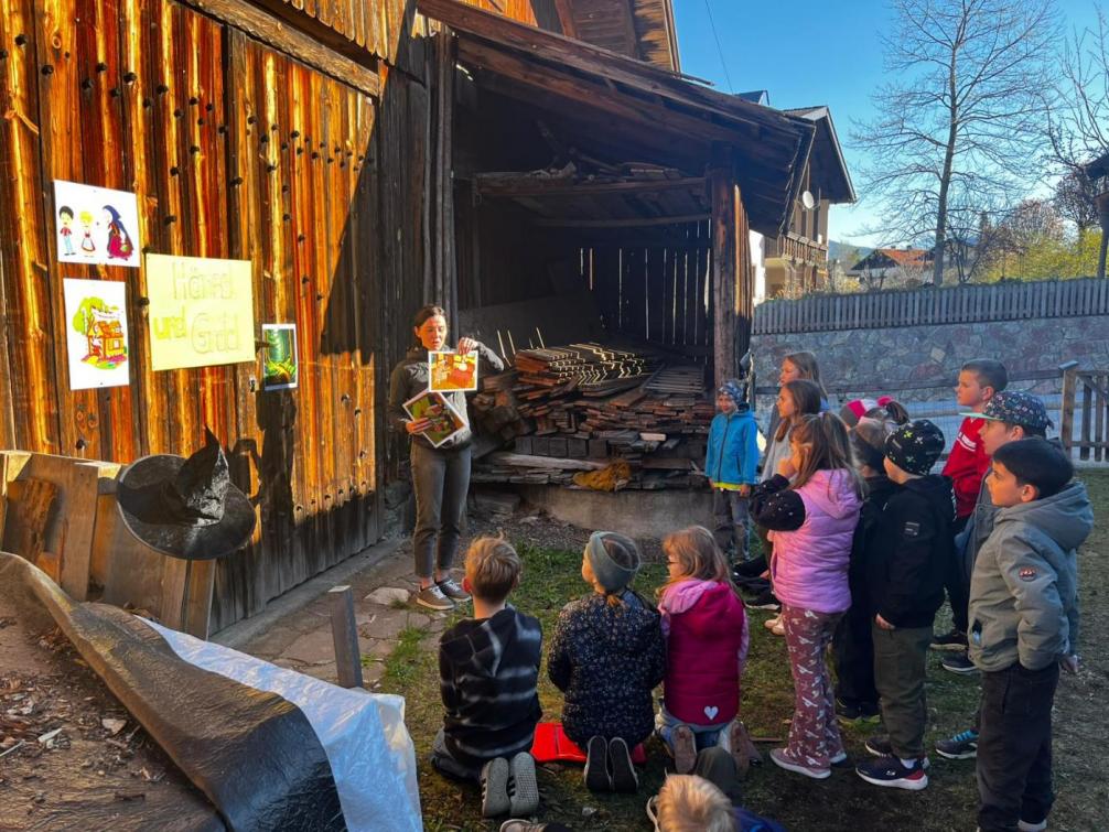 Kinder hören das Märchen vor dem Stadl
